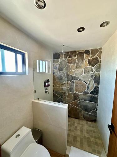 a bathroom with a toilet and a stone wall at Siempre Valle Hotel Boutique in Valle de Guadalupe