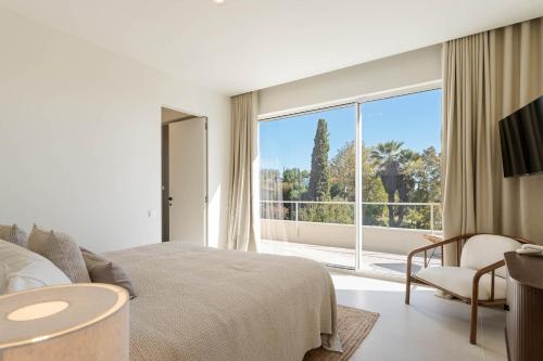 a bedroom with a bed and a large window at Modern Sea View Villa, Heated Pool,Rooftop Jacuzzi Outdoor Kitchen 12min faro Airport in Santa Bárbara de Nexe