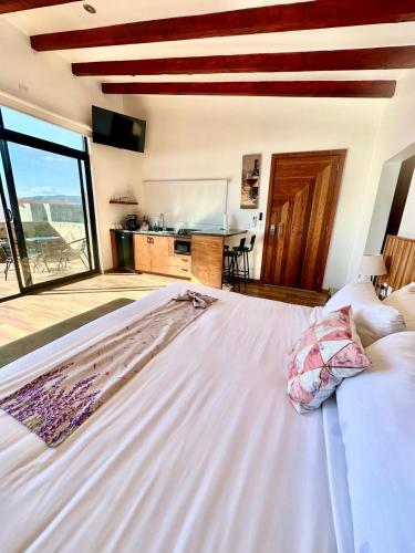 a large white bed in a room with a kitchen at Siempre Valle Hotel Boutique in Valle de Guadalupe