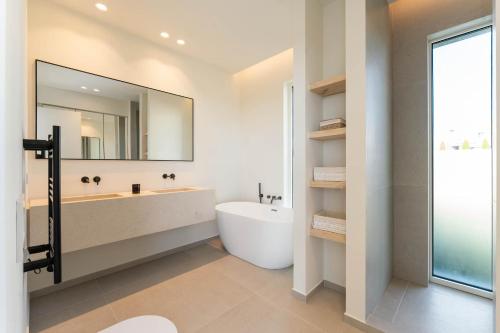 a bathroom with a tub and a sink and a mirror at Modern Sea View Villa, Heated Pool,Rooftop Jacuzzi Outdoor Kitchen 12min faro Airport in Santa Bárbara de Nexe