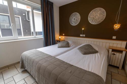 a bedroom with a bed with two pillows on it at Hotel Tesselhof in De Koog