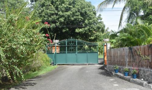 a green gate in a driveway with a fence at Gite d'Arles Bungalow "Orchidée" in Le Moule