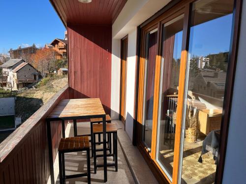a balcony with a wooden table and two stools at Valberg 3 pièces au pied des pistes in Péone