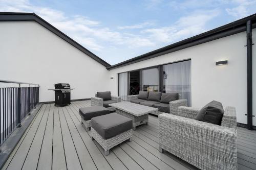 a deck with furniture and a grill on a house at BayView Luxury 3 Bedroom Apartment First Floor in Downings