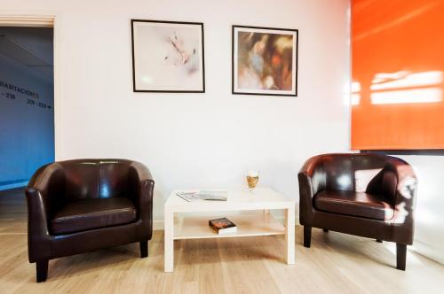 two leather chairs and a table in a room at Hotel LB Villa De Cuenca in Cuenca