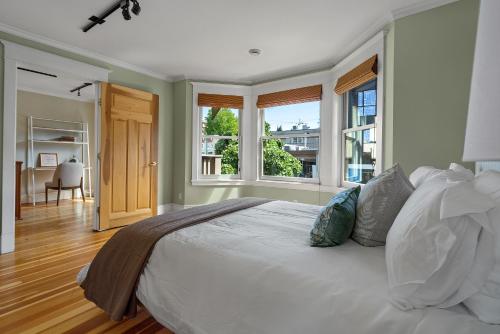 Schlafzimmer mit einem großen weißen Bett und Fenstern in der Unterkunft The Vancouver Heritage Home - Mount Pleasant in Vancouver