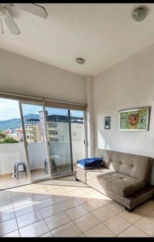 a living room with a couch and a large window at Apartment 4 Maleconcito del Sol Barra de Navidad in Barra de Navidad