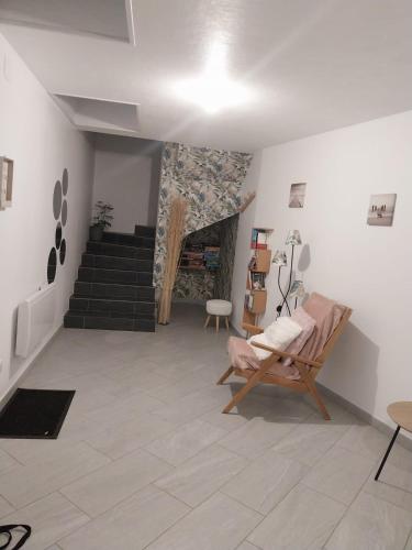 a living room with a chair and a staircase at Le murmure du ruisseau - Pièce de vie 60 m2 - Terrasse 30 M2 - 2 WC in Sémeries