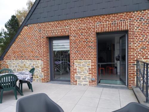 a brick building with a patio with a table and chairs at Le murmure du ruisseau - Pièce de vie 60 m2 - Terrasse 30 M2 - 2 WC in Sémeries