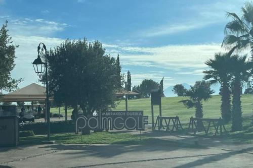 a park with picnic tables and palm trees and a sign at appart jardin de l atlas Marrakech Waky Beach Golf Montagne de l Atlas in Marrakech