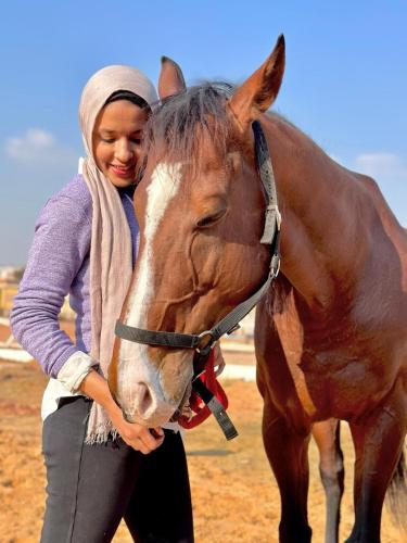 a woman standing next to a brown horse at Ramage Hotel & Resort in Cairo