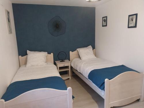 a bedroom with two beds and a clock on the wall at Le murmure du ruisseau - Pièce de vie 60 m2 - Terrasse 30 M2 - 2 WC in Sémeries