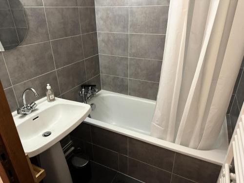 La salle de bains est pourvue d'un lavabo, d'une baignoire et d'un rideau de douche. dans l'établissement Résidence Ecrin Des Glaciers Daim - ECRIN DES GLACIERS D43 MAE-7511, à Combloux