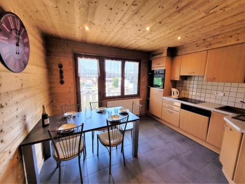 une cuisine avec une table, des chaises et une horloge dans l'établissement Résidence Beau Sejour - Appartement confortable, situation centrale MAE-7561, aux Gets