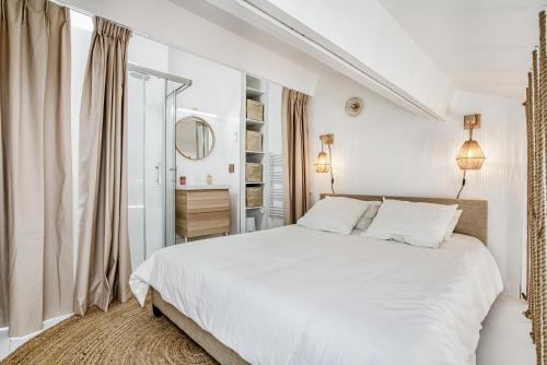 - une chambre blanche avec un lit blanc et un miroir dans l'établissement My little St-Tropez, à Saint-Tropez