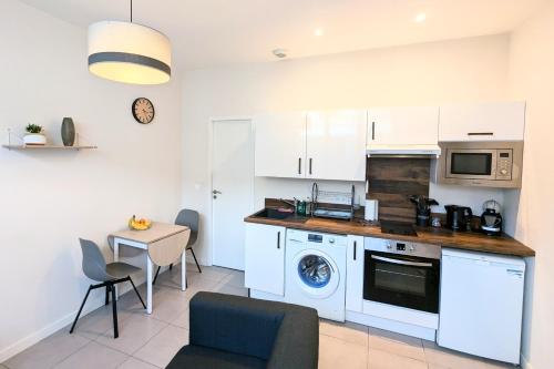 une cuisine avec des armoires blanches, une table et un micro-ondes dans l'établissement T2 en plein cœur de Dax proche des thermes, à Dax