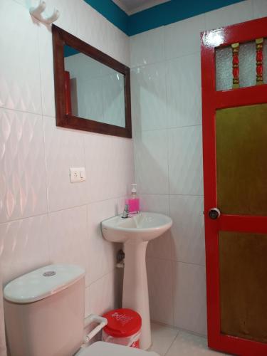 a bathroom with a toilet and a sink and a red door at MariaAuxiliadora in Monguí