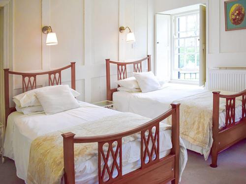 Un dormitorio con dos camas y una ventana. en Tor Royal Farm House, en Princetown