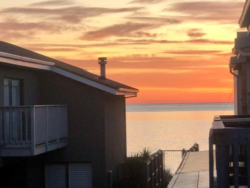 a house on the beach with a sunset in the background at BEACH Living - “A bit of Mykonos near Mordialloc!” in Aspendale
