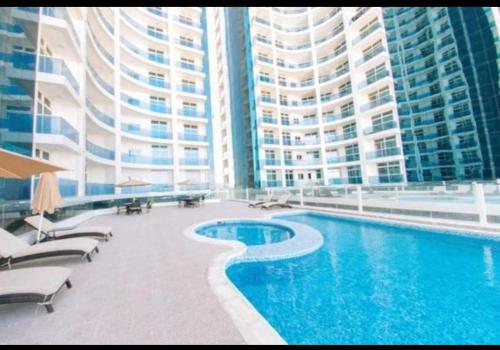 a swimming pool in front of a large building at Cheap Holiday Homes in Ajman