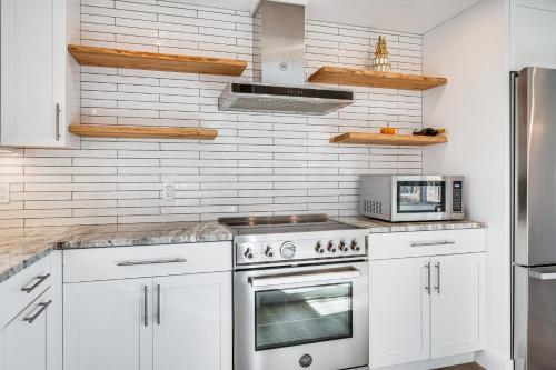 a kitchen with white cabinets and a stove top oven at Custom-Built Home Near Piscataqua River! in Eliot