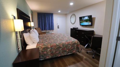 a hotel room with a bed and a desk and a television at Royal Inn Cochran in Cochran