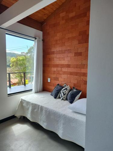 a bedroom with a bed with a large window at Chalé Vista pra Lombada in Conceição da Ibitipoca