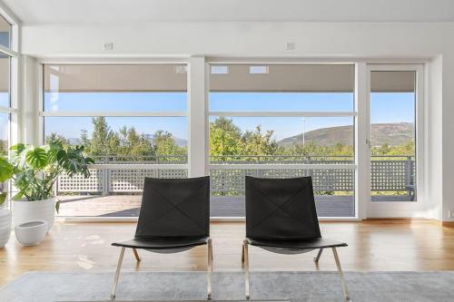 two chairs in a living room with a large window at Elegant 4BR villa with great views and location in Tromsø