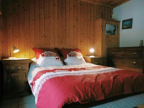 a bedroom with a bed with red sheets and white pillows at La Grand'Raie Table d'hôtes in Les Gras