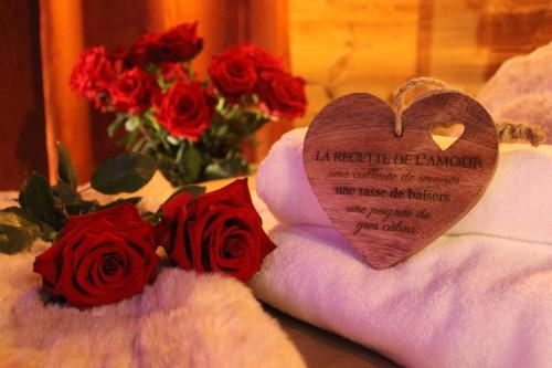 a heart sitting on a towel next to red roses at Love room la bohème in Baccarat