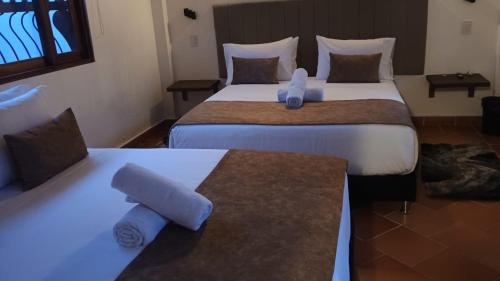 two beds in a hotel room with towels on them at Hotel Santa Barbara Sachica in Villa de Leyva