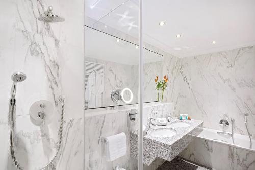 a white bathroom with a shower and a sink at Hotel Stadt Freiburg in Freiburg im Breisgau