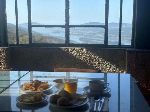 a glass table with two plates of food and orange juice at Convento San Payo in Vila Nova de Cerveira