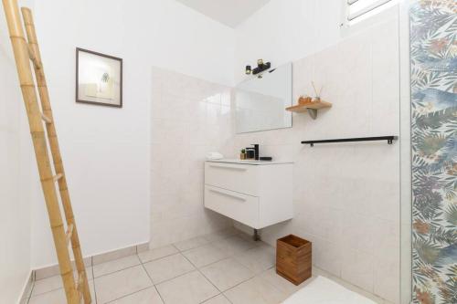 a white bathroom with a sink and a shower at Villa Aïoli confortable avec piscine in Sainte-Rose