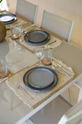 a table with two black plates and glasses on it at Villa Aïoli confortable avec piscine in Sainte-Rose