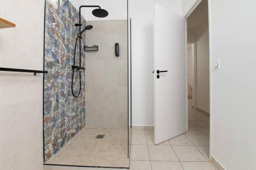 a shower with a glass door in a bathroom at Villa Aïoli confortable avec piscine in Sainte-Rose