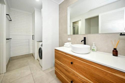 a bathroom with a sink and a washing machine at Coastal Comfort, Relaxing Kings Beach Retreat in Caloundra