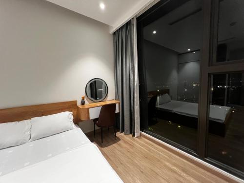 a bedroom with a bed and a desk with a mirror at Căn 2 ngủ Landmark 2 Ecopark view hồ đẹp in HÆ°ng YÃªn