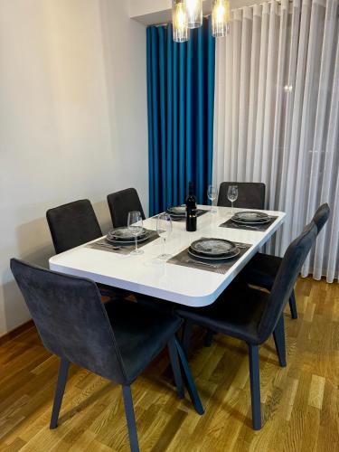 a dining room table with black chairs and a blue curtain at BISI penthouse in Skopje