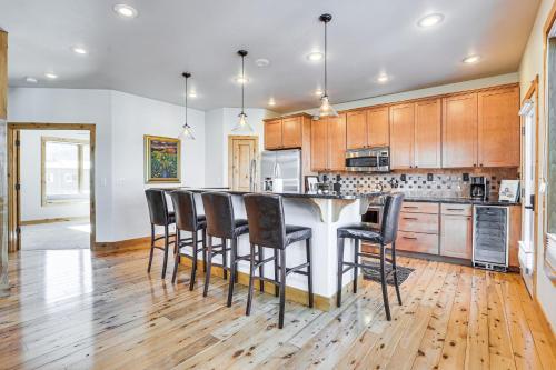 a kitchen with wooden cabinets and a bar with stools at Dtwn Frisco Home with Mtn View, 11 Mi to Ski Breck! in Frisco