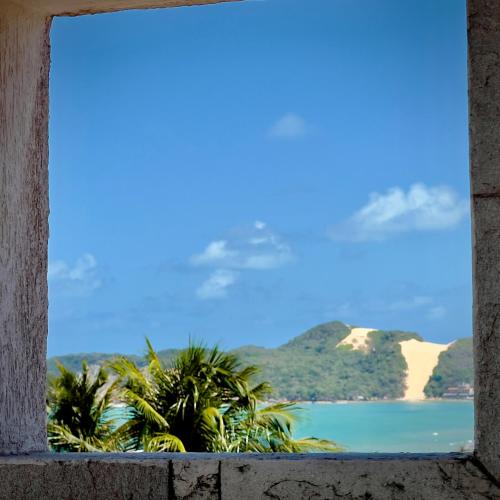 a window with a view of the ocean and palm trees at Residence Dunas Exclusive in Natal