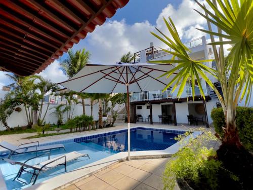 a villa with a swimming pool and an umbrella at Residence Dunas Exclusive in Natal