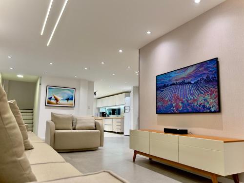 a living room with a couch and a tv on the wall at Residence Dunas Exclusive in Natal
