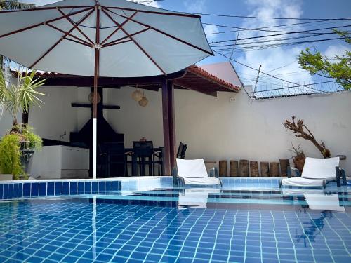 a swimming pool with an umbrella and two chairs and a table at Residence Dunas Exclusive in Natal