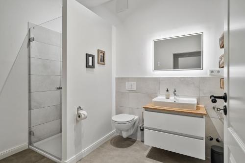 a white bathroom with a sink and a toilet at Tofthof dree in Westerhever