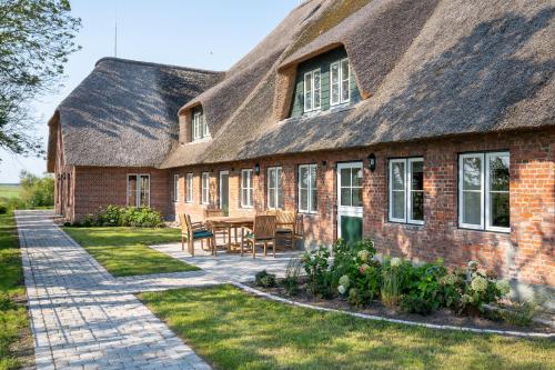 an old brick house with a thatched roof and a patio at Tofthof dree in Westerhever