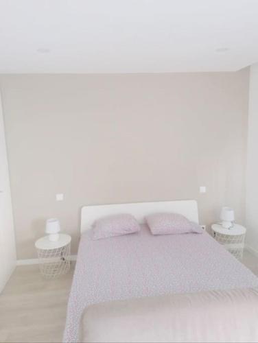 a white bedroom with a bed and two tables at Cantinho do Fórum IV in Aveiro