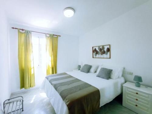 a white bedroom with a large bed and a window at Live Abades Playa y terraza in Abades