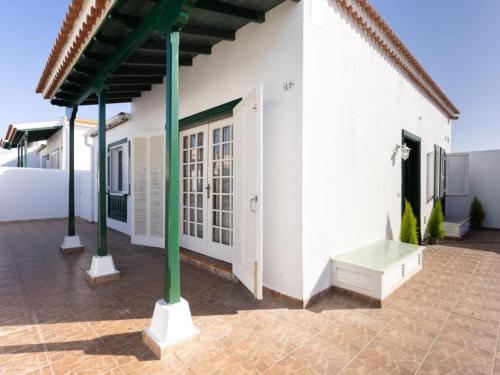 a white house with green columns and a porch at Live Abades Playa y terraza in Abades