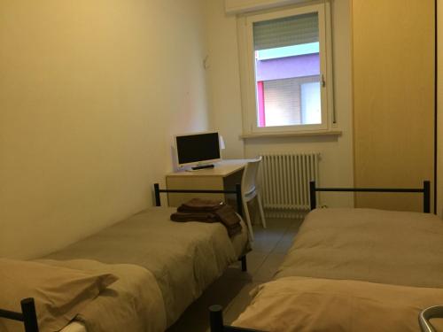 a room with two beds and a desk with a computer at Residence La Nave in Senigallia